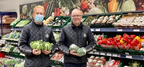 Shop workers holding vegetables